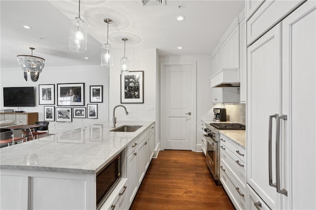 kitchen with dark hardwood / wood-style flooring, sink, built in appliances, white cabinetry, and hanging light fixtures