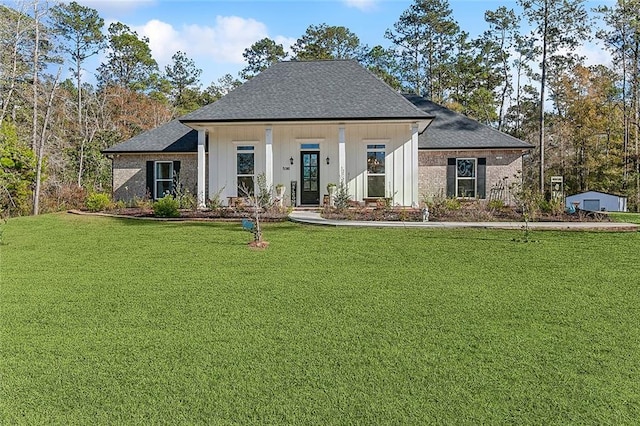 view of front of home with board and batten siding, brick siding, a shingled roof, and a front lawn