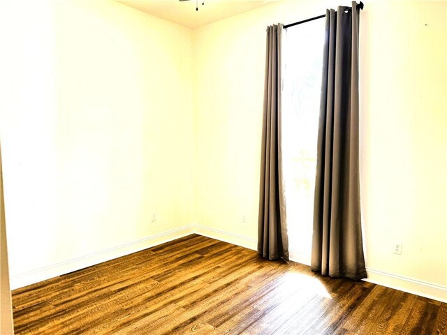 empty room featuring dark wood-style floors and baseboards