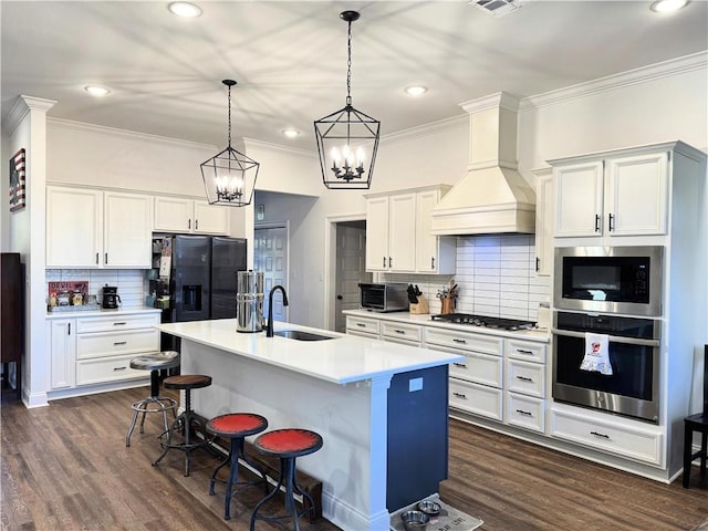 kitchen featuring dark wood finished floors, appliances with stainless steel finishes, light countertops, premium range hood, and a sink