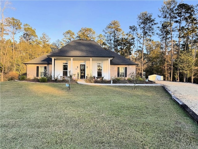 view of front of house featuring board and batten siding, a front yard, and an outdoor structure