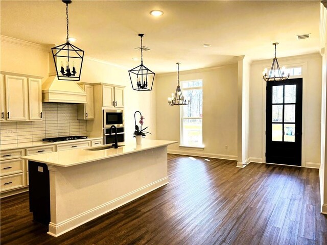 kitchen with tasteful backsplash, visible vents, appliances with stainless steel finishes, a kitchen island with sink, and a sink