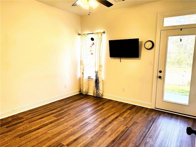 unfurnished living room featuring baseboards, dark wood-type flooring, and a healthy amount of sunlight