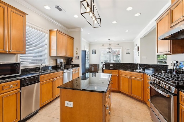 kitchen with sink, stainless steel appliances, a center island, decorative light fixtures, and dark stone counters