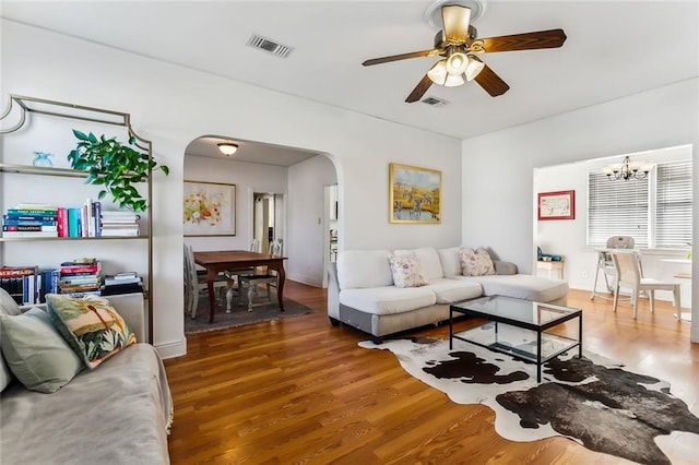 living room with hardwood / wood-style floors and ceiling fan with notable chandelier