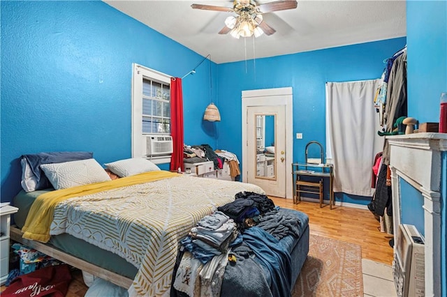 bedroom featuring wood-type flooring, ceiling fan, and cooling unit