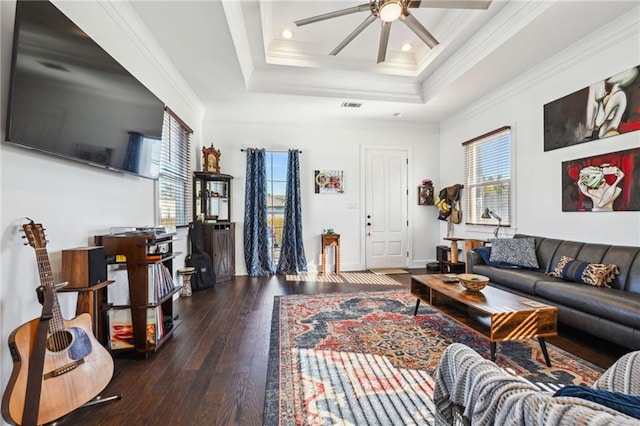 living room featuring a raised ceiling, ceiling fan, dark wood-type flooring, and ornamental molding