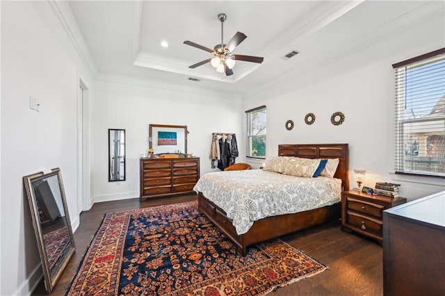 bedroom with a tray ceiling, ceiling fan, crown molding, and dark hardwood / wood-style floors