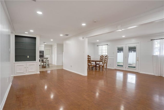 unfurnished living room featuring wood-type flooring, ornamental molding, and french doors