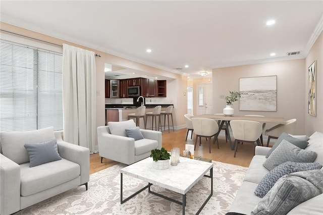 living room featuring crown molding and light hardwood / wood-style flooring