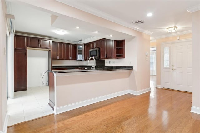 kitchen with stainless steel microwave, sink, ornamental molding, dark brown cabinets, and kitchen peninsula