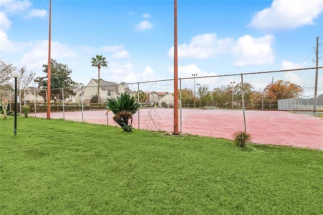 view of tennis court featuring a yard