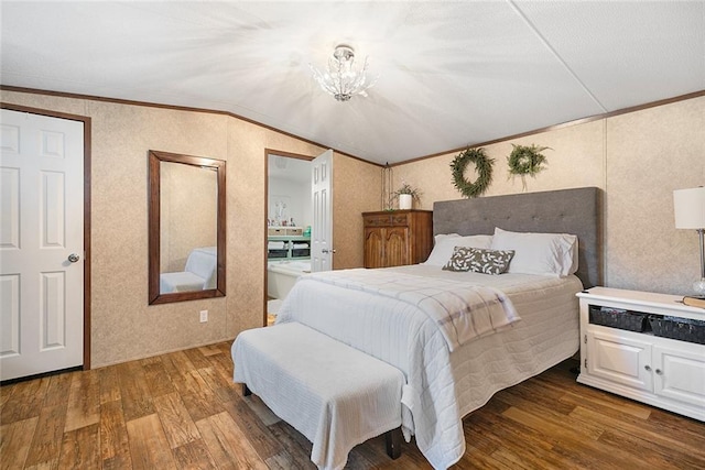 bedroom featuring ensuite bath, hardwood / wood-style floors, vaulted ceiling, and ornamental molding