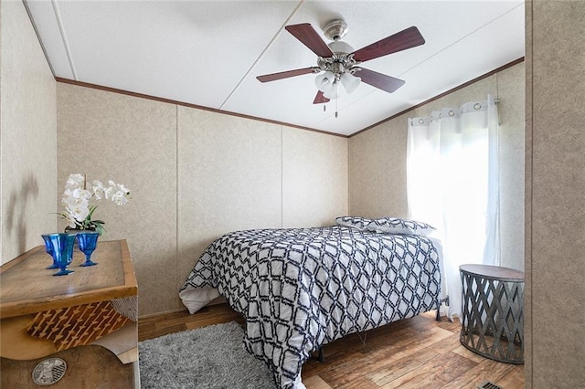 bedroom with hardwood / wood-style flooring, ceiling fan, and crown molding