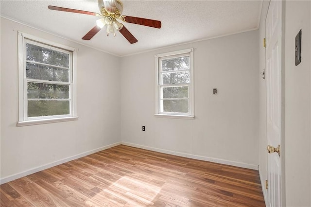 empty room with a textured ceiling, hardwood / wood-style flooring, and a wealth of natural light