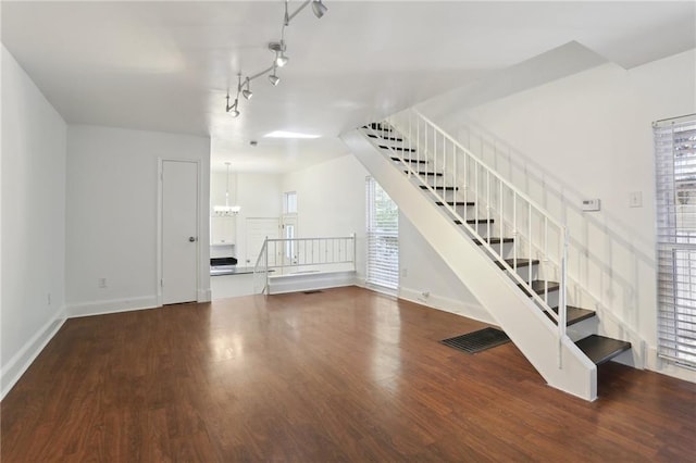 stairway with wood-type flooring and an inviting chandelier