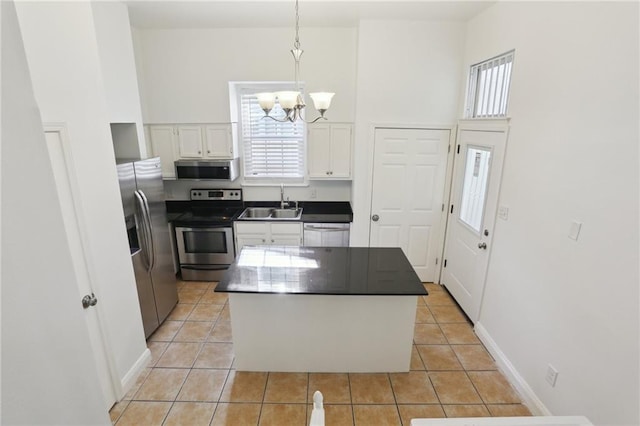 kitchen featuring appliances with stainless steel finishes, decorative light fixtures, a chandelier, a center island, and white cabinetry