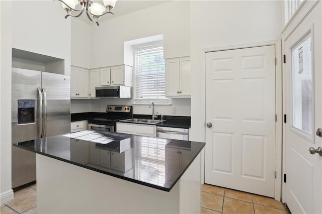 kitchen featuring a center island, white cabinets, light tile patterned flooring, stainless steel appliances, and a chandelier