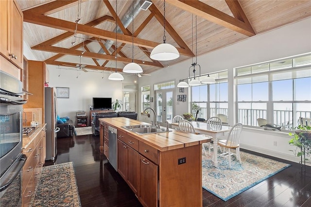 kitchen with wood counters, appliances with stainless steel finishes, a kitchen island with sink, wooden ceiling, and beamed ceiling