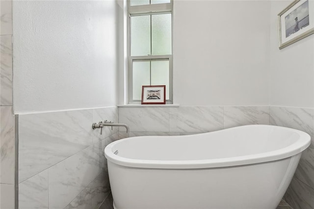 bathroom featuring a washtub and tile walls