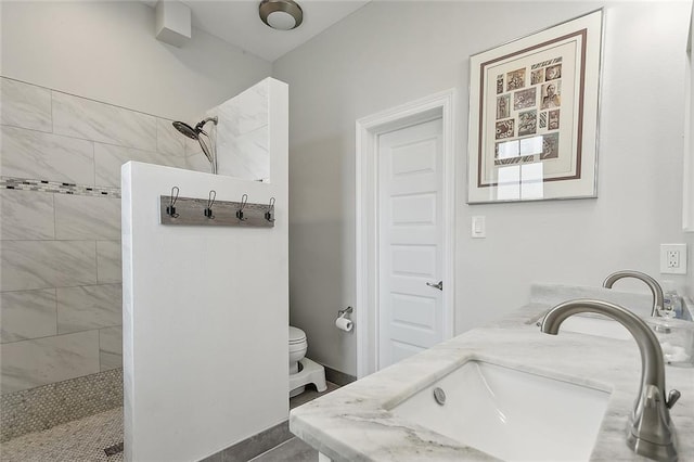 bathroom with tile patterned flooring, toilet, vanity, and tiled shower