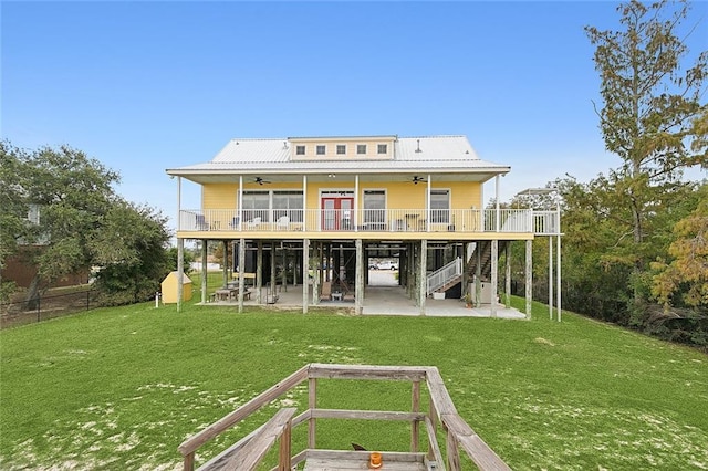 back of property featuring a lawn, ceiling fan, a deck, and a patio