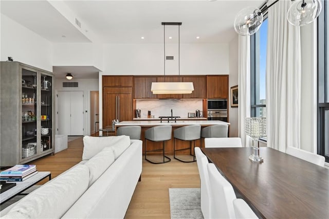 living room featuring a towering ceiling and light hardwood / wood-style flooring