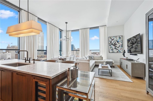 kitchen featuring pendant lighting, sink, a notable chandelier, light hardwood / wood-style floors, and a wall of windows