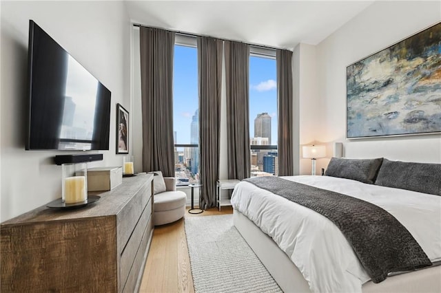 bedroom with expansive windows and light hardwood / wood-style flooring