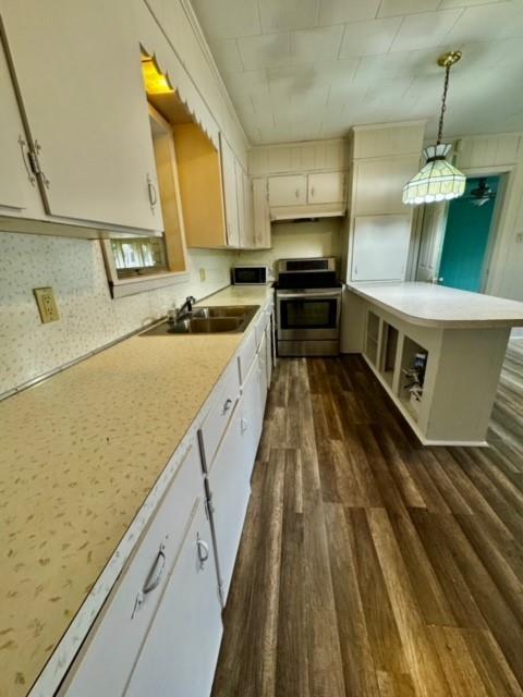 kitchen with white cabinets, decorative light fixtures, sink, and stainless steel stove