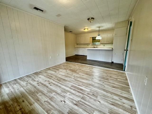 unfurnished living room with light hardwood / wood-style flooring and wood walls