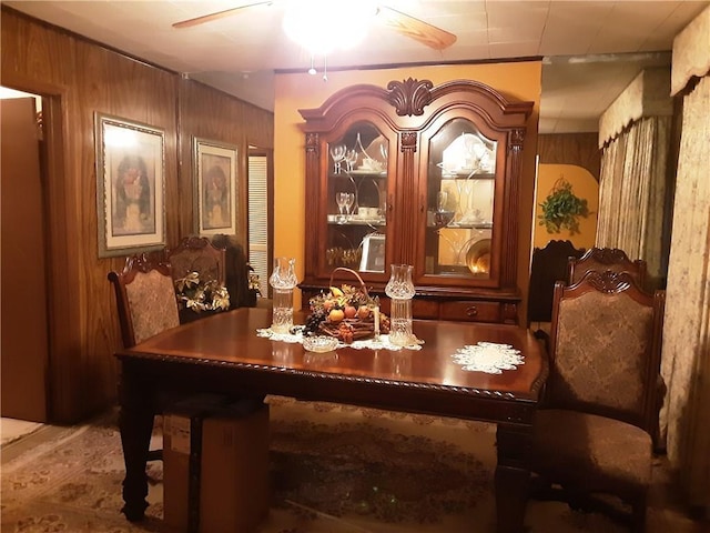 dining area featuring ceiling fan and wood walls