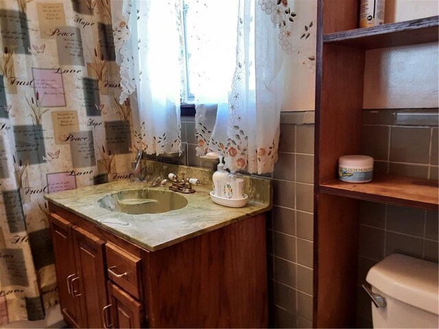 bathroom featuring toilet, vanity, tile walls, and decorative backsplash