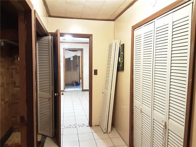 corridor featuring light tile patterned floors and ornamental molding