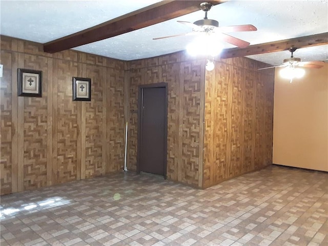 unfurnished room featuring a textured ceiling, wooden walls, and beamed ceiling