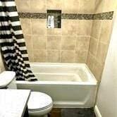 full bathroom featuring vanity, shower / tub combo, and toilet