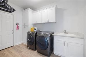 washroom with cabinets, washer and dryer, sink, and light hardwood / wood-style flooring