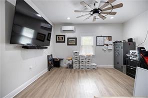 office space with ceiling fan, a wall mounted AC, and light wood-type flooring