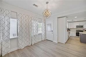 interior space with ornamental molding, a notable chandelier, and light hardwood / wood-style floors