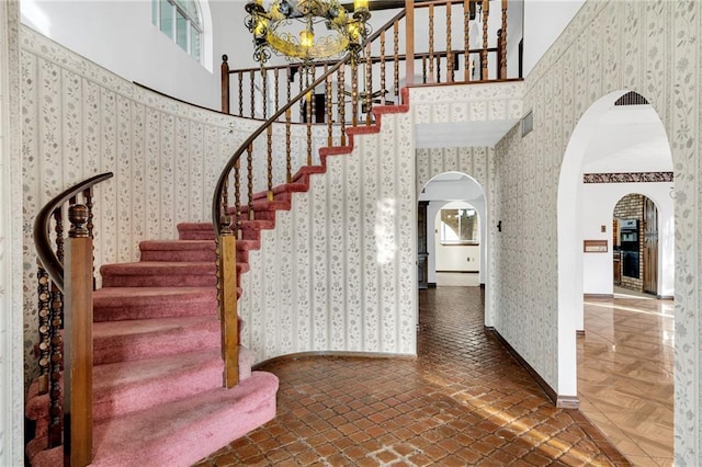 staircase with a towering ceiling and an inviting chandelier