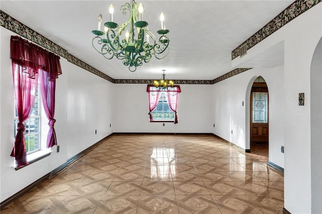 unfurnished dining area featuring a chandelier and parquet flooring