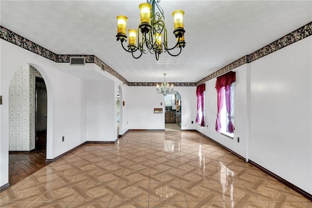 unfurnished dining area featuring parquet flooring, a textured ceiling, and a notable chandelier