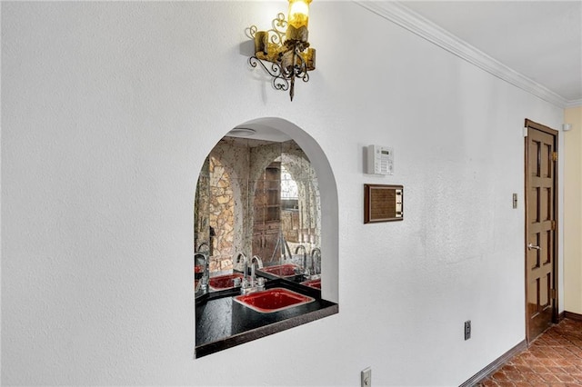 hall featuring dark tile patterned flooring, crown molding, and sink