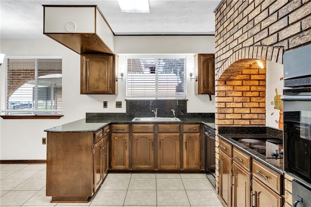 kitchen with sink, light tile patterned floors, black appliances, and a textured ceiling