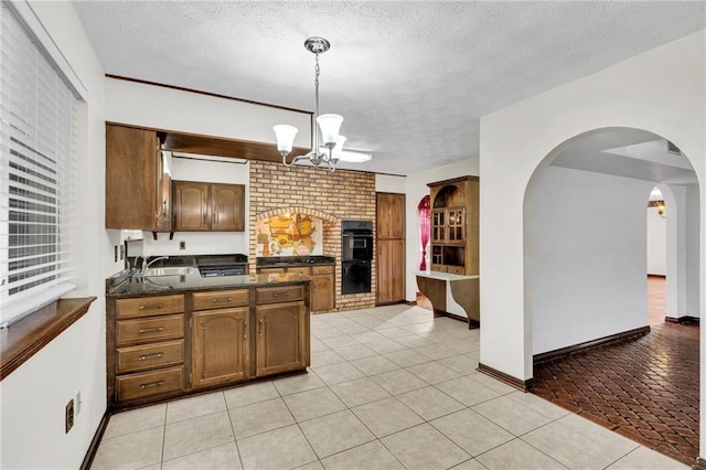 kitchen featuring a textured ceiling, black double oven, sink, pendant lighting, and a chandelier