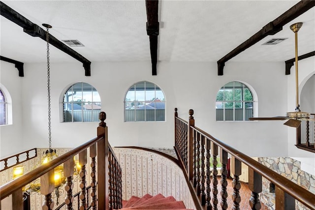 stairway with beamed ceiling and an inviting chandelier