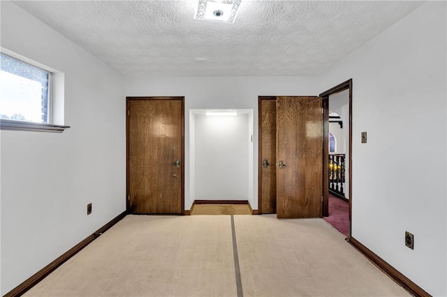 unfurnished bedroom with light colored carpet and a textured ceiling