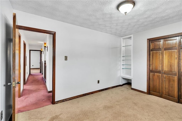 unfurnished bedroom featuring a textured ceiling, light colored carpet, and a closet