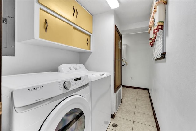 clothes washing area featuring electric panel, washer and clothes dryer, light tile patterned flooring, and cabinets