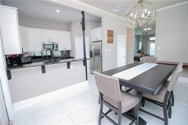 dining space featuring sink, ornamental molding, and an inviting chandelier